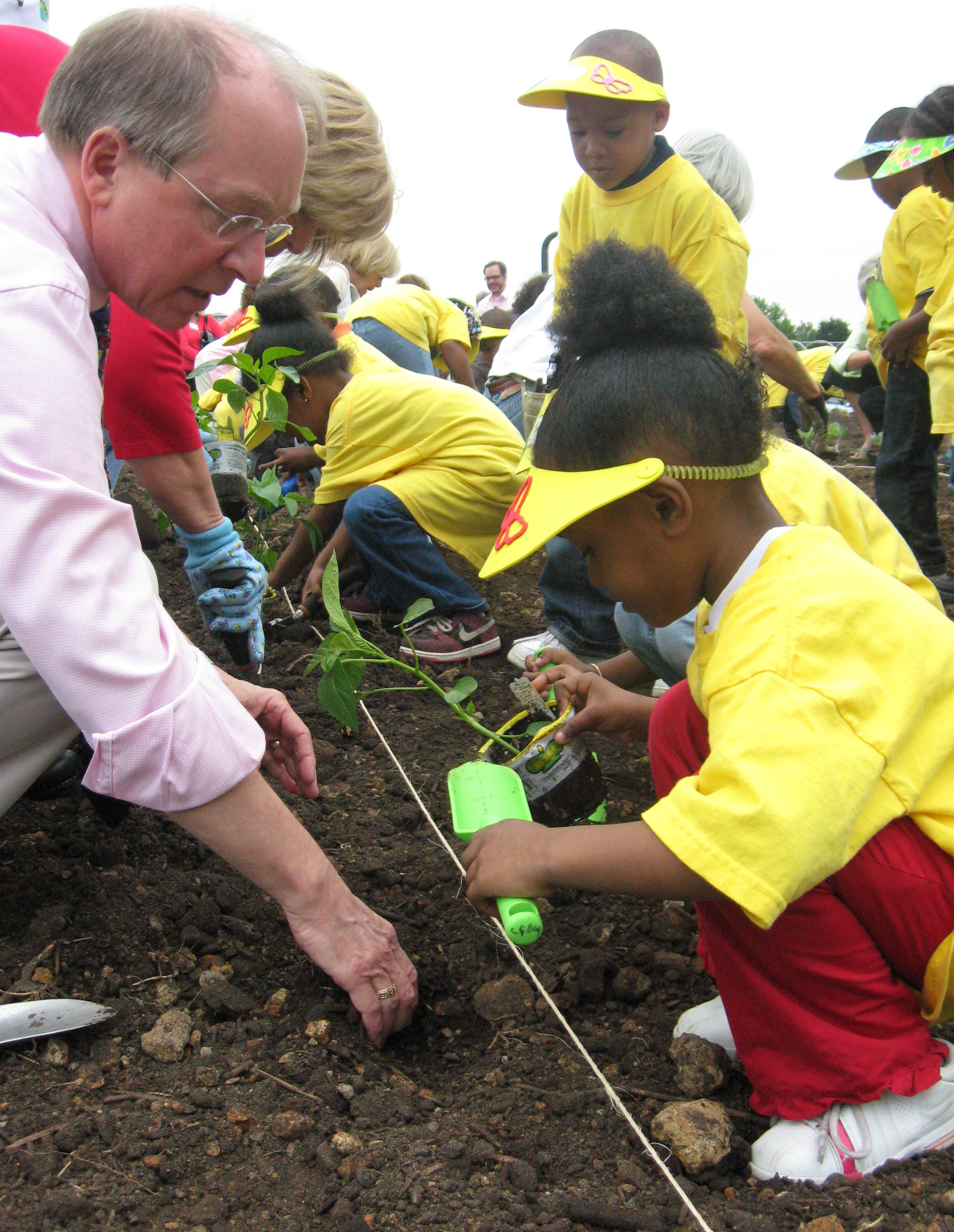 Frank Robinson helping a child plant. 