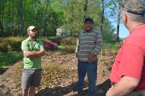 From left to right: Chris Brown, Oscar Gamaz, and Wes Morgan revisit the time when Brown was stung by a wasp, right after Morgan noted that for all the time he had ever worked there, he'd never been stung by one. They really enjoy throwing jokes at each other, laughing heartily as they work outside.