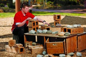 Tristin Compton rearranges objects in the Children's Garden