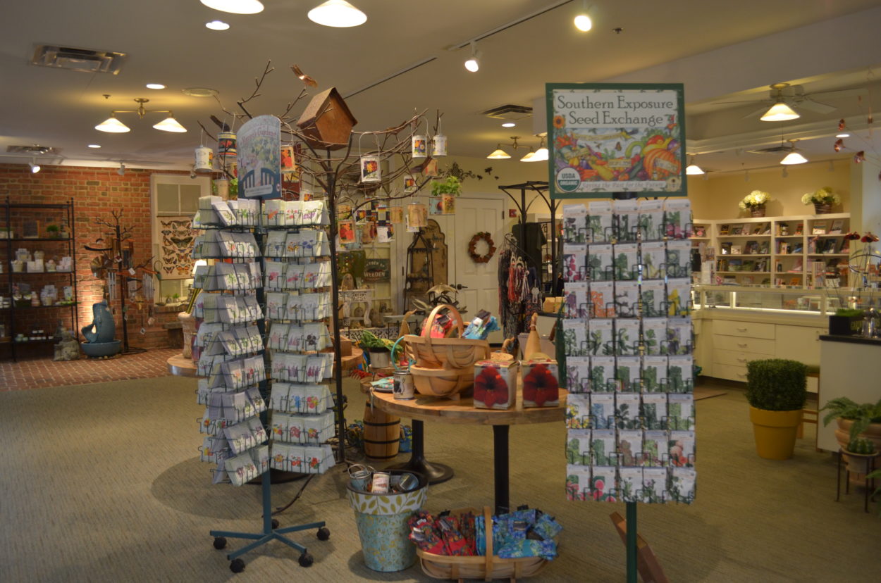 Garden display featuring two racks of seeds and various gardening supplies in the background. 