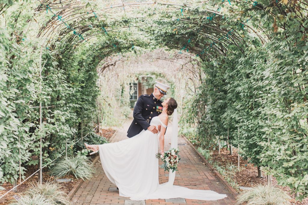 A Marine and bride in the tunnel of trees kissing -- Weddings at Lewis Ginter are always magical