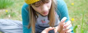 Girl examining a dandelion as part of a citizen science project in her backyard. Image by Mitra Bryant