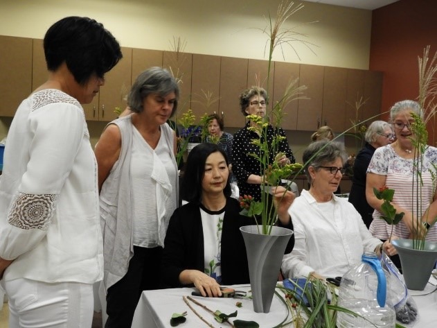 Group of people surrounding an Ikebana floral arrangment