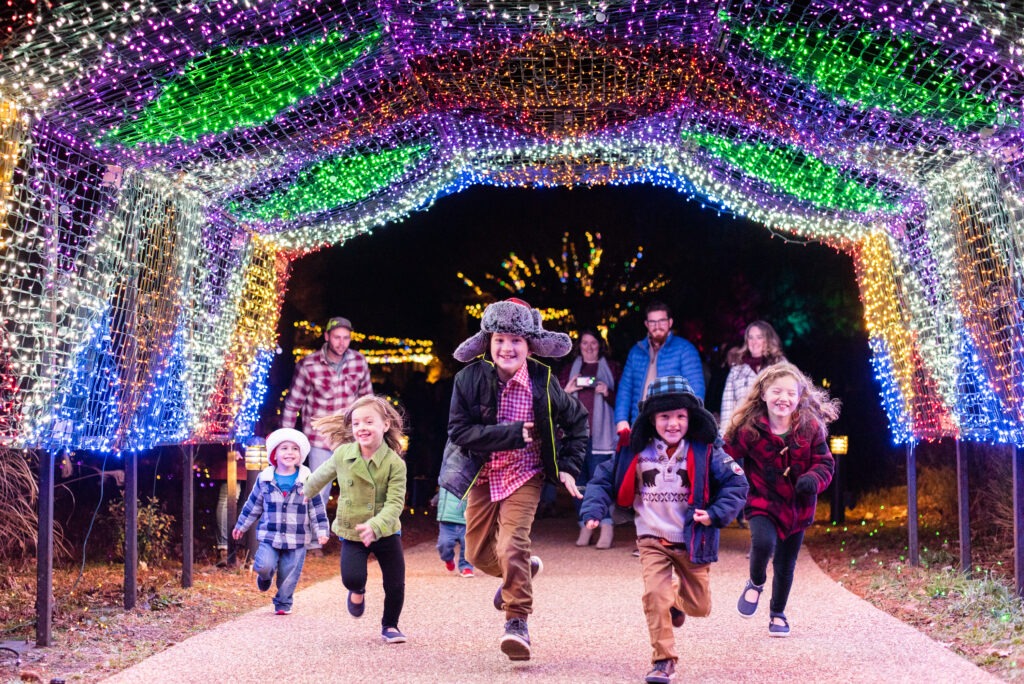 Kids running through light tunnel at Dominion Energy GardenFest of Lights