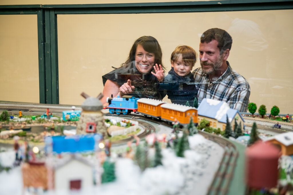 A family looks at the model trains in the Kelly Education Center during Dominion Energy GardenFest of Lights at Lewis Ginter Botanical Garden.